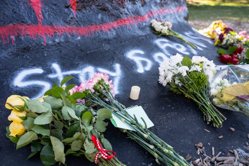 Students leave flowers at the foot of the Rock on Farm Lane on Feb. 14, 2023, one day after a mass shooting took place in Michigan State University's North Neighborhood.