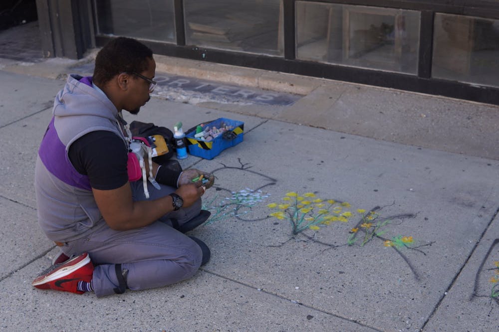 <p>During clean-up efforts June 1, Lansing artist Ryan Holmes painted flowers intertwining with the words of the message &quot;F--- 12&quot; that was left during a protest the night before. </p>