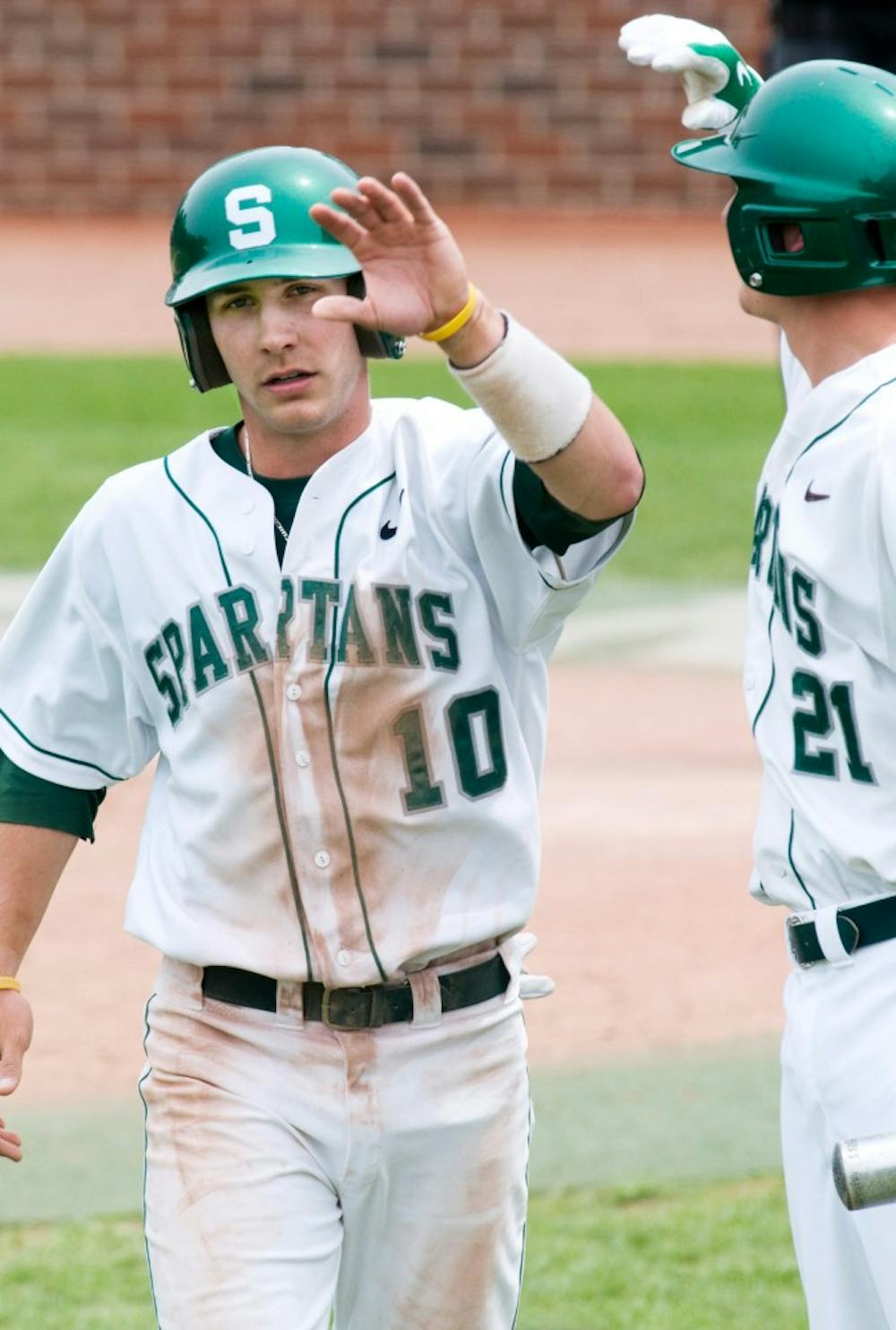 Second baseman freshman Ryan Jones high fives his teammate, senior infielder Chris Roberts after scoring a run during Saturday's game against Indiana University. Jones hit for the cycle, helping to boost the Spartan's to a 10-4 victory over the Hoosiers in the second game of the three game series. The State News File Photo