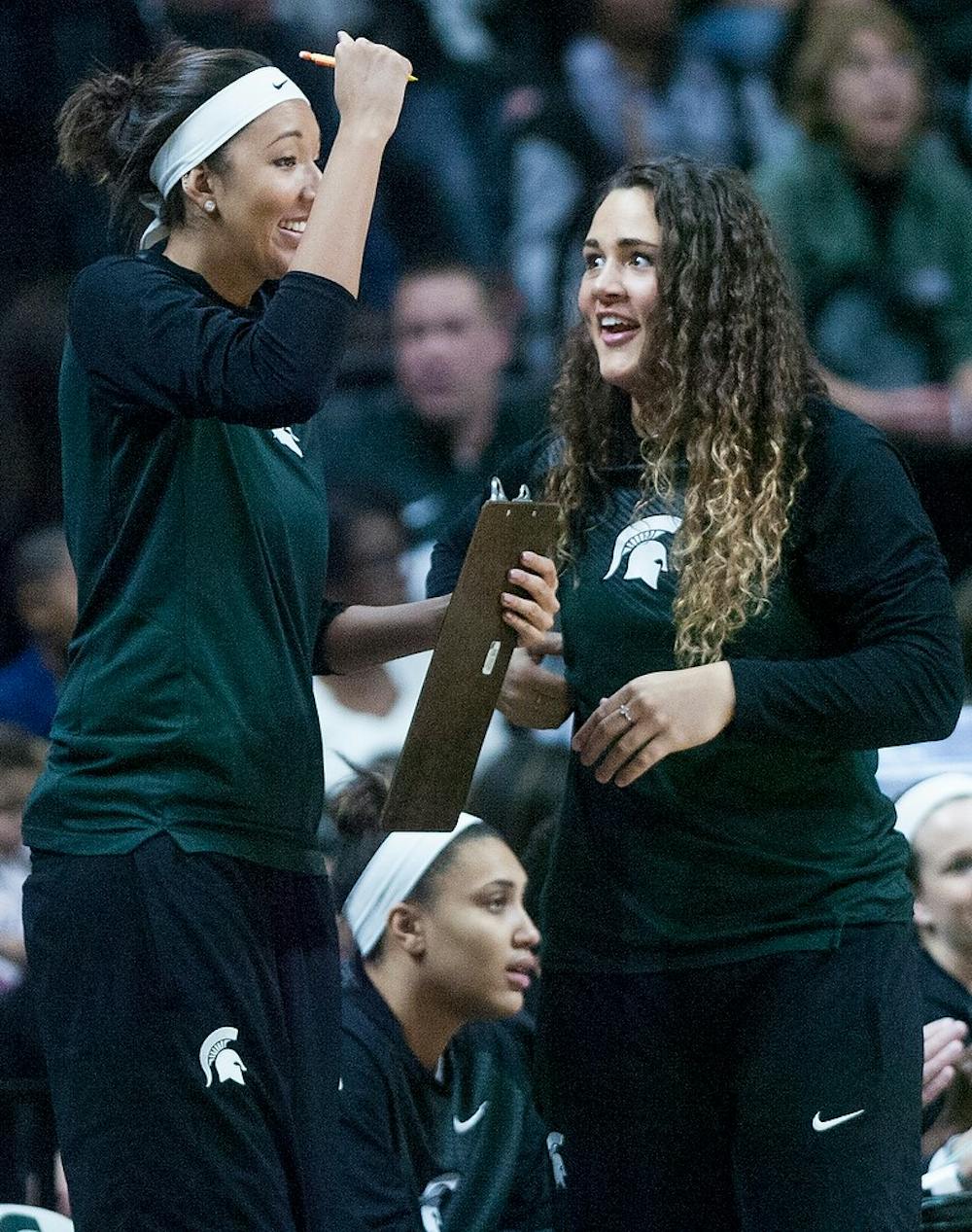 <p>Senior center Jasmine Hines, right and senior center Madison Williams cheer for their teammates Jan. 18, 2015, during the game against Iowa at Breslin Center. The Spartans were defeated by the Hawkeyes, 52-50. Erin Hampton/The State News</p>