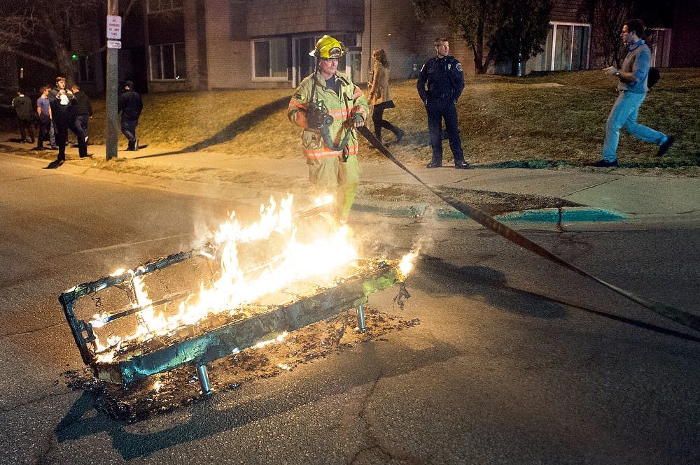 	<p>A firefighter stands to extinguish a couch fire in the intersection of River Street and Victor Street in Cedar Village during the early hours Saturday after the men&#8217;s basketball team lost to Duke in the fourth round of the <span class="caps">NCAA</span> Tournament. The East Lansing Police Department responded to numerous fire disturbances Saturday morning.</p>