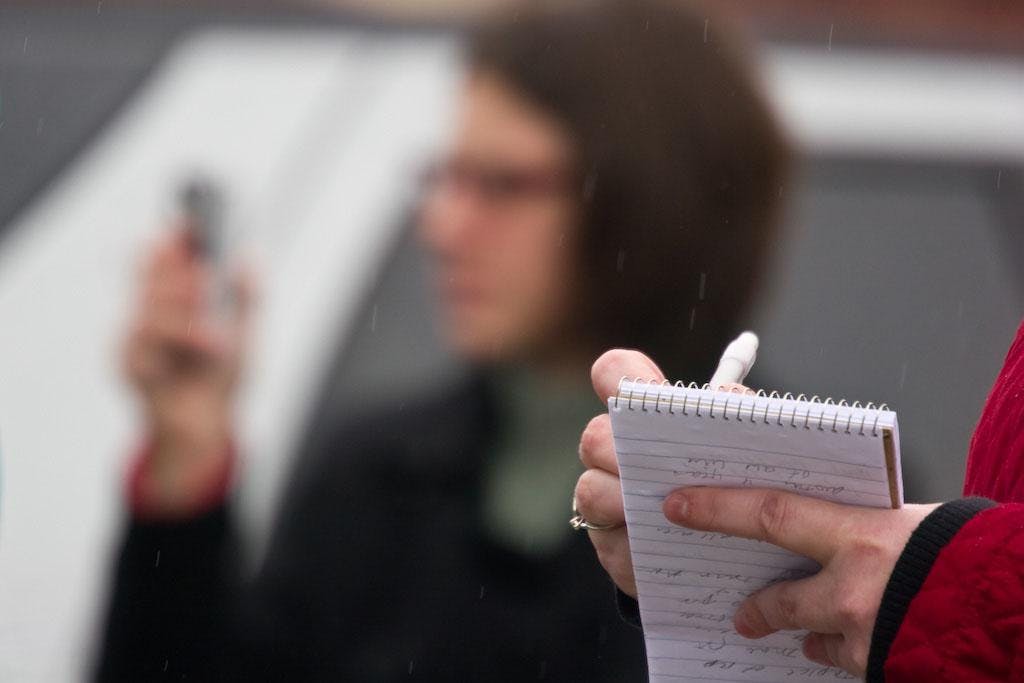 A reporter scribes in their notebook