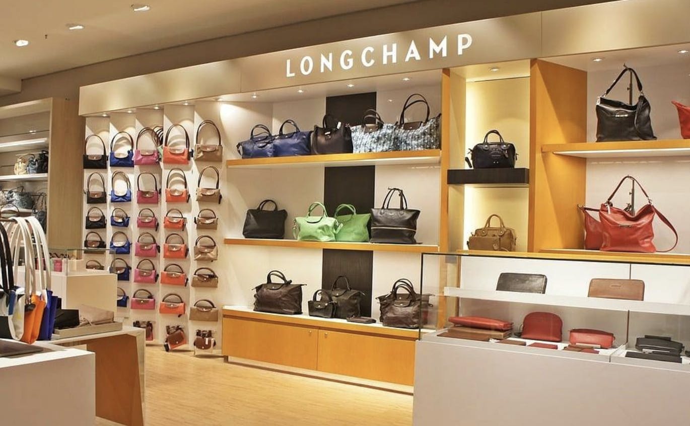 A longchamp store with many handbags on display.