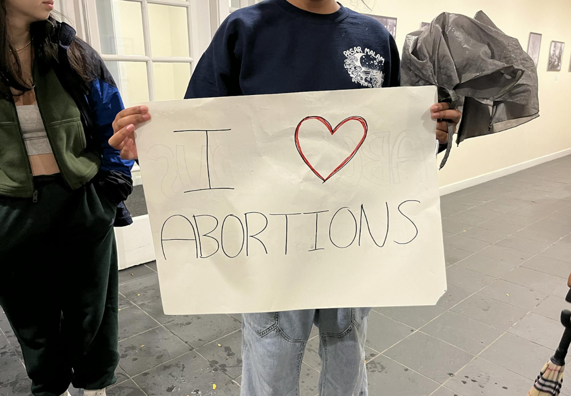 A protester is pictured holding a sign outside the Alumnae Lounge on Sept. 29.