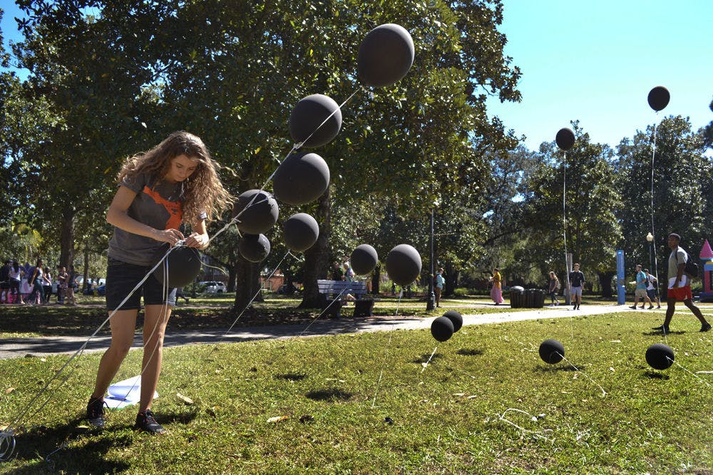 <p>Amani Flood, a 19-year-old UF digital arts and sciences sophomore, untangles a bunch of black balloons on the Plaza of the Americas on Oct. 15, 2015. Each of the 24 balloons represented 500,000 displaced Syrians in the refugee crisis. "We want to make an impact to get more refugees in the United States," said Flood, who helped collect student signatures on a petition to open the U.S. to Syrian refugees.</p>