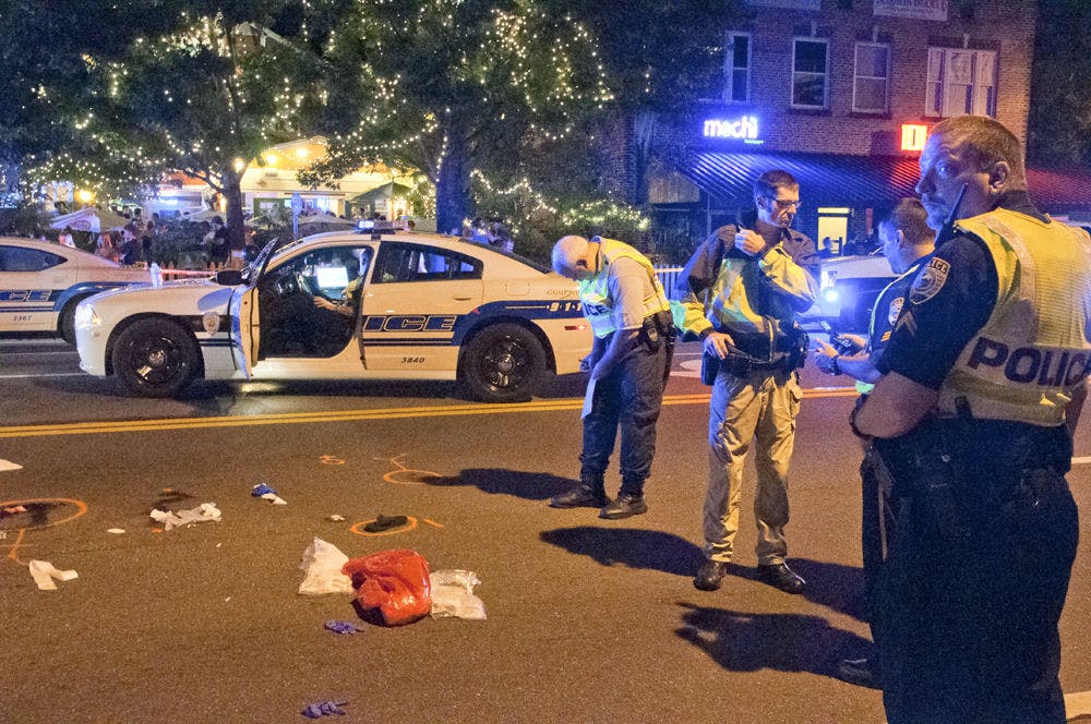 Police stand on West University Avenue after a man and woman were struck by a car while crossing the street without a signal Friday night.