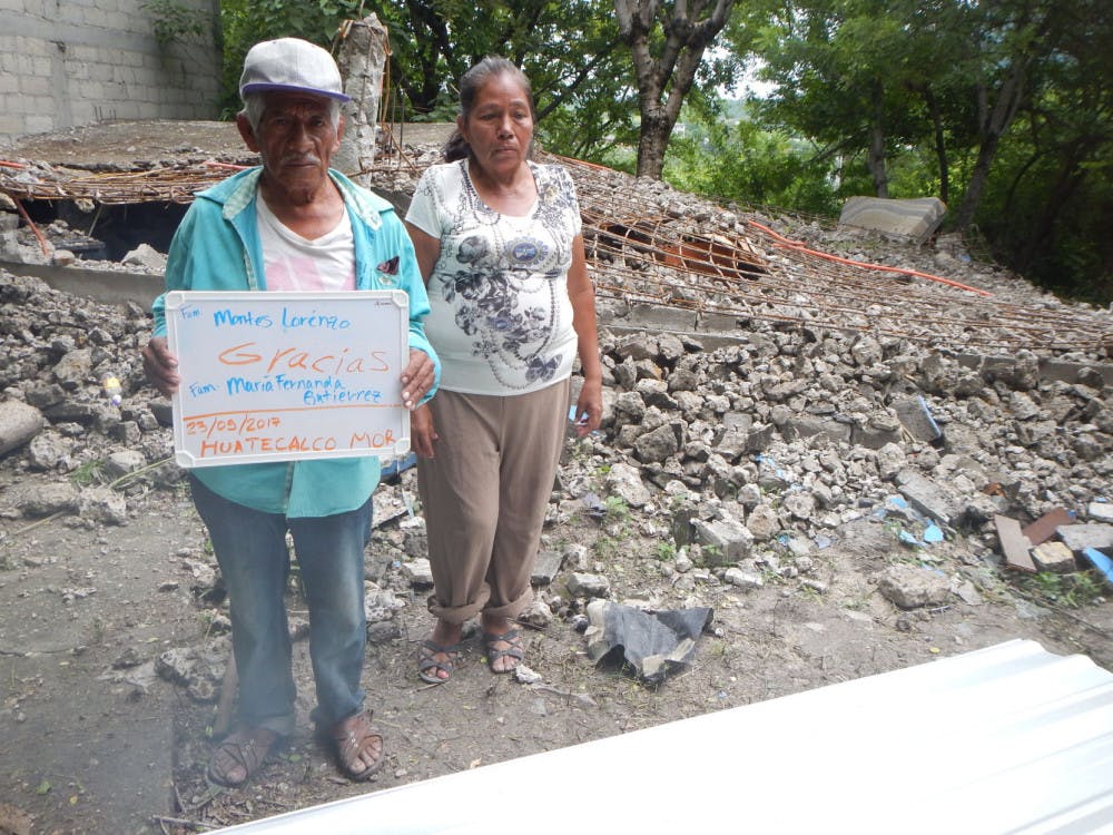 An elderly couple thanks the person who donated materials for their temporary shelter in Huatecalco, Mexico. Their collapsed home lies in the background.