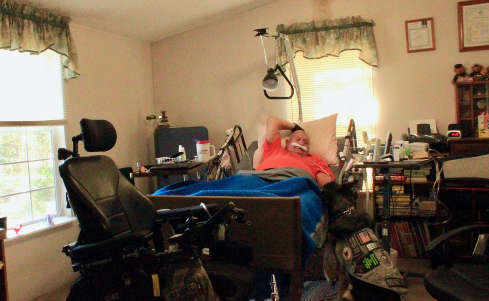 Michael Gaither, a U.S. Army veteran suffering from multiple sclerosis, lays in bed with his service dog, Honey, by his side. Both are fighting terminal illnesses and need constant medical treatments.