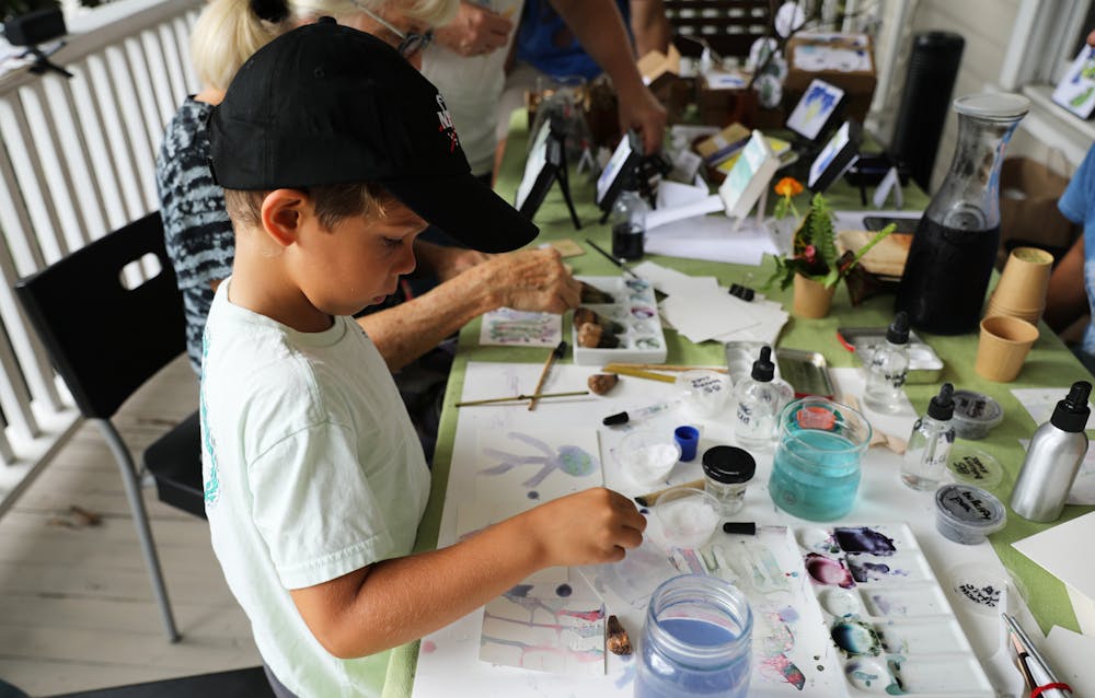 Dylan Perez, 6, uses blue butterfly flower pigment to paint on reusable paper at an eco-art event on Saturday, June 12, 2021. 