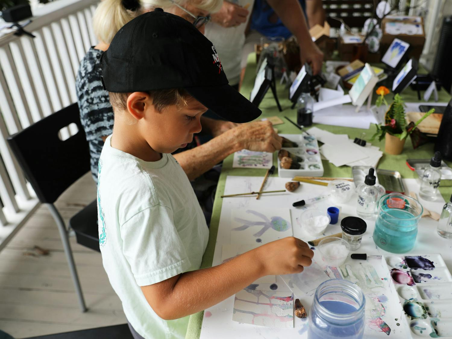 Dylan Perez, 6, uses blue butterfly flower pigment to paint on reusable paper at an eco-art event on Saturday, June 12, 2021.