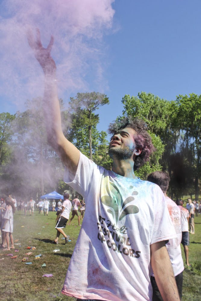 Deepanshu Soni, an information systems and operations management senior, flings colored powder in the air on Hume Field on Sunday. The 23-year-old threw the powder as part of UF Holi, a traditional Indian holiday that celebrates the coming of spring.