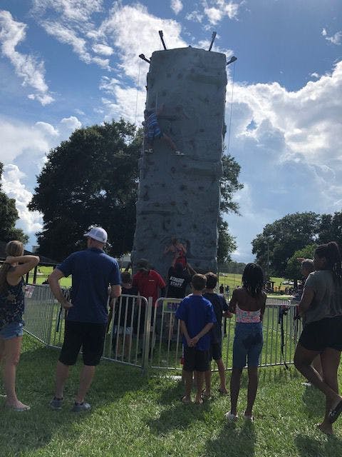 A crowd gathers to watch two people climb the rock climbing wall.
&nbsp;