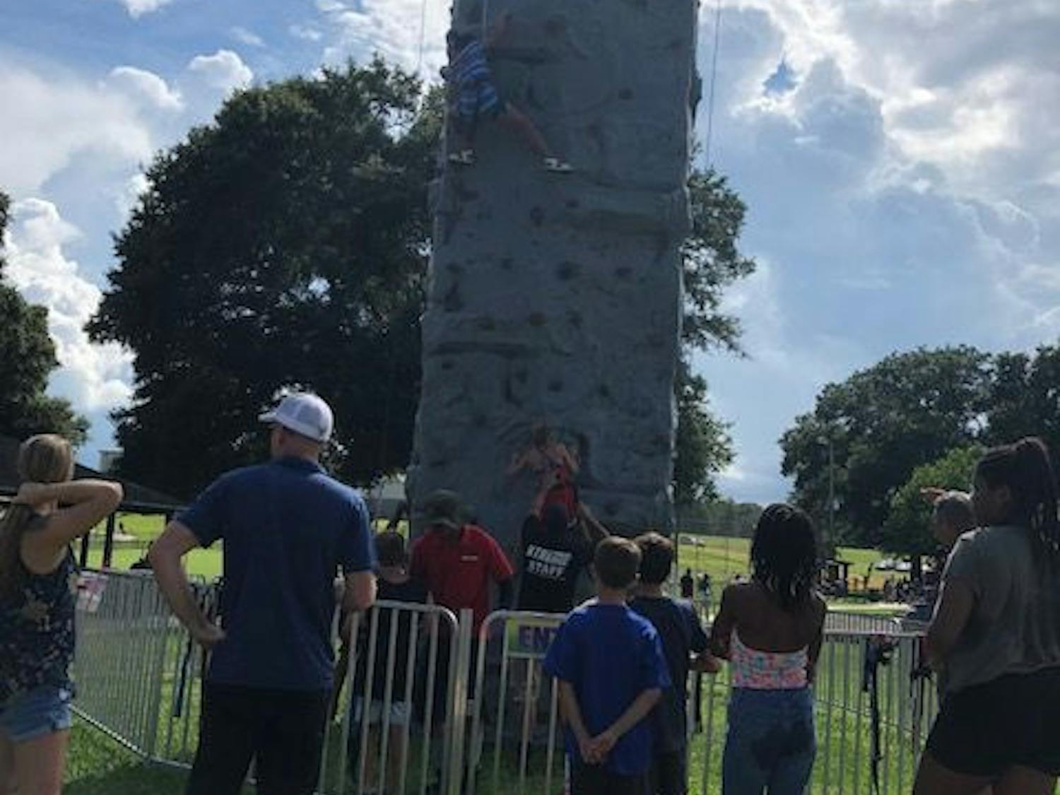 A crowd gathers to watch two people climb the rock climbing wall.
&nbsp;