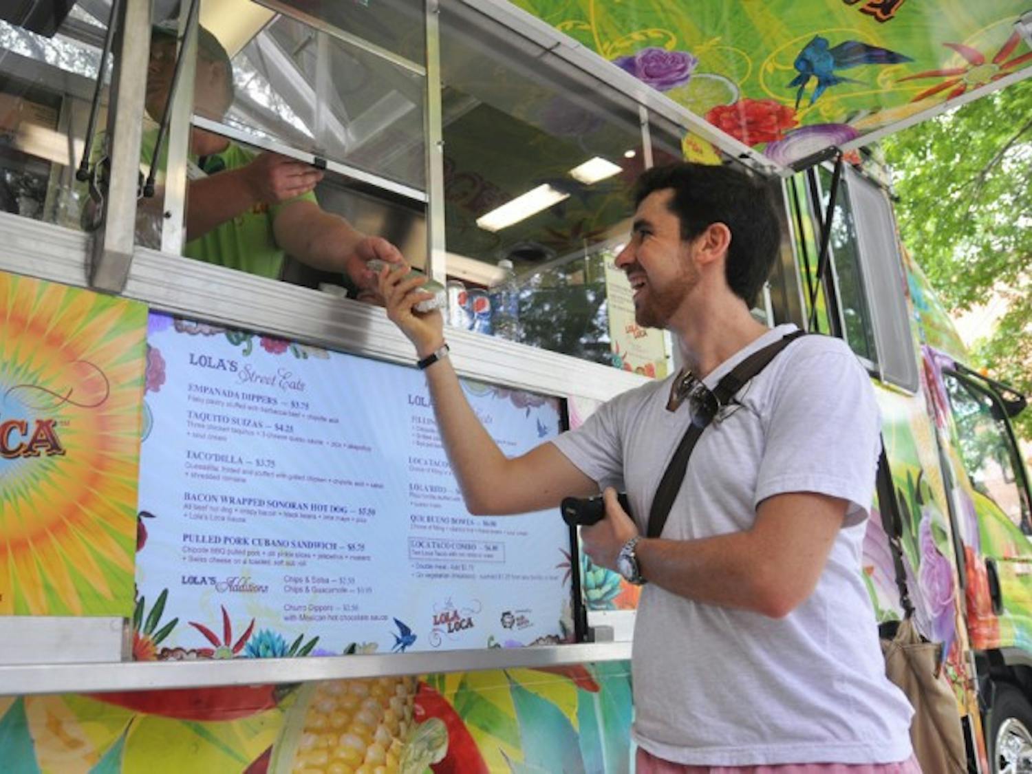 Stefan Wolff, a 20-year-old economics junior, grabs a pulled pork cubano candwich for lunch at the La Lola Loca food truck near the Plaza of the Americas on Tuesday.