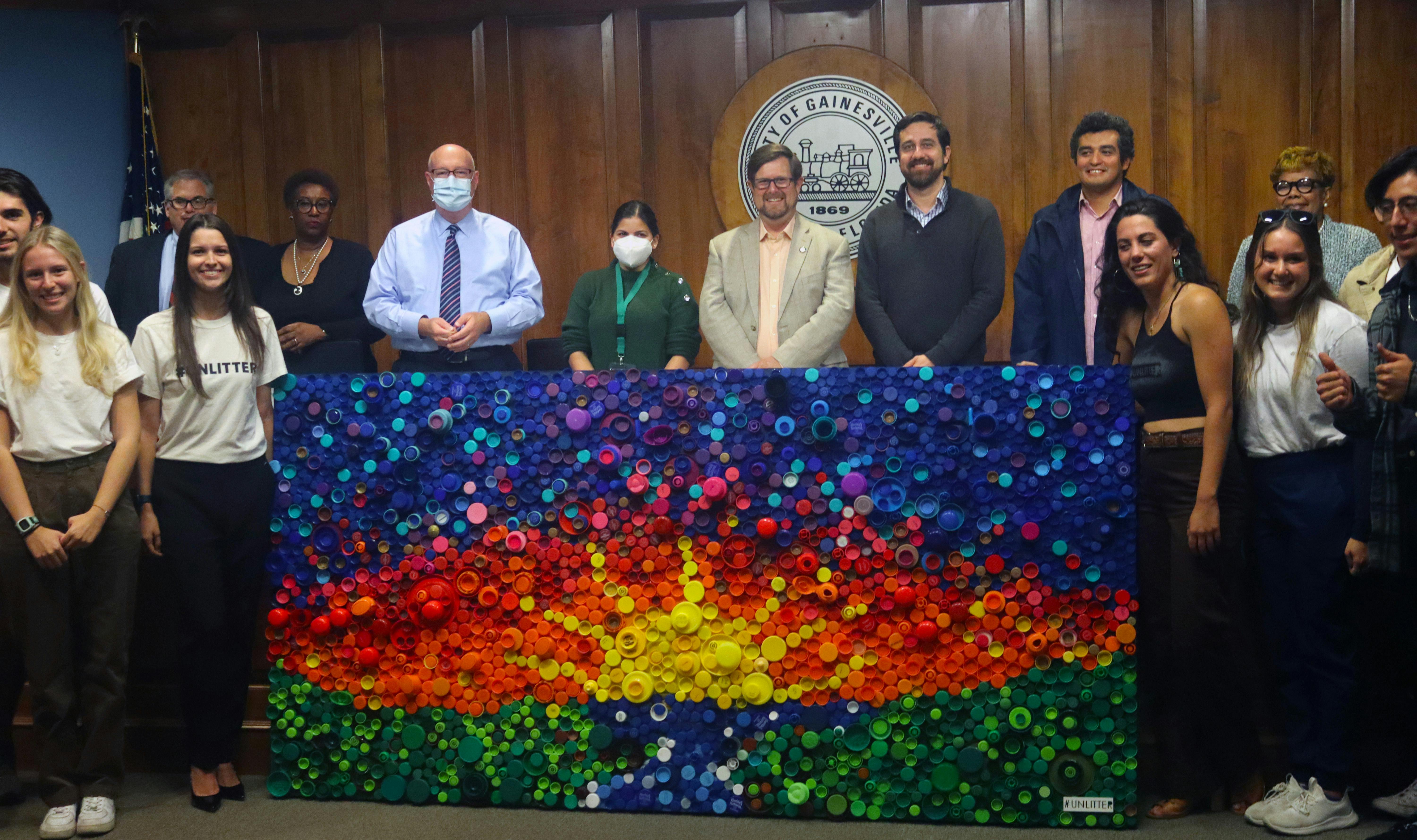 Mayor Lauren Poe, city officials and members of #UNLITTER line up around the bottle cap mural after its unveiling at City Hall Thursday, Oct. 20, 2022.