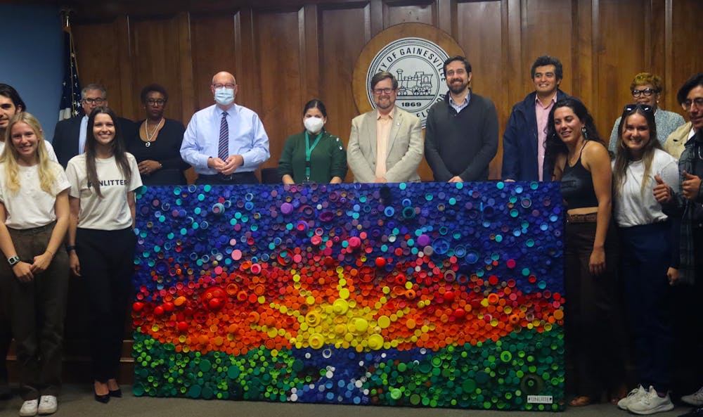 <p>Mayor Lauren Poe, city officials and members of #UNLITTER line up around the bottle cap mural after its unveiling at City Hall Thursday, Oct. 20, 2022.</p>