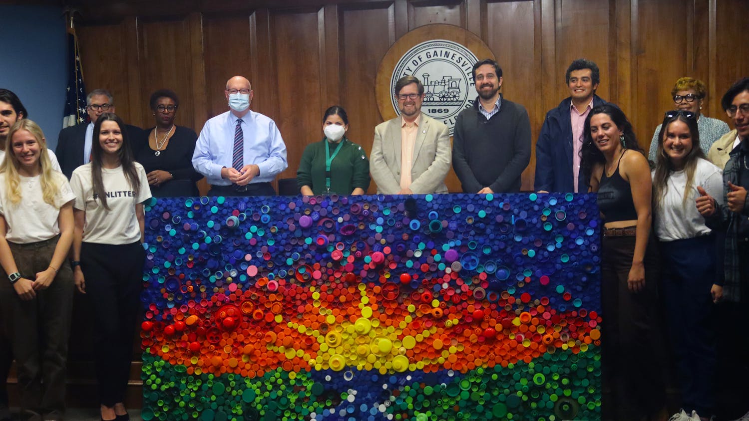 Mayor Lauren Poe, city officials and members of #UNLITTER line up around the bottle cap mural after its unveiling at City Hall Thursday, Oct. 20, 2022.