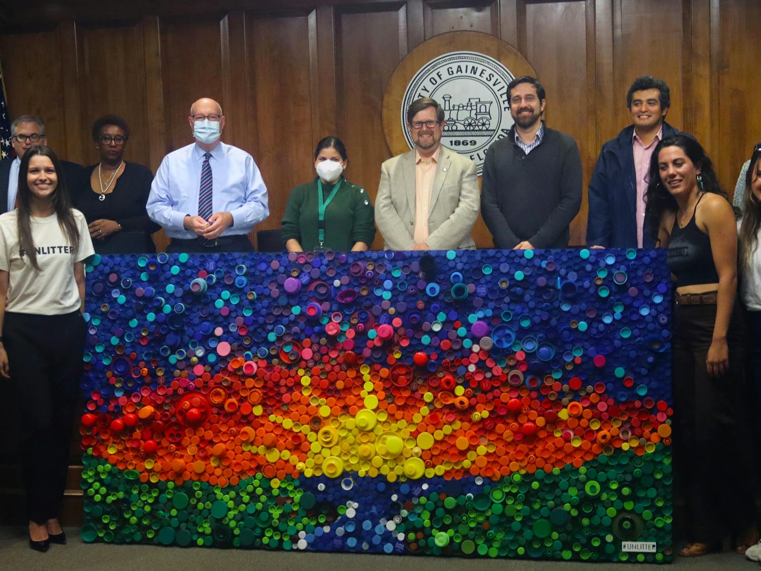 Mayor Lauren Poe, city officials and members of #UNLITTER line up around the bottle cap mural after its unveiling at City Hall Thursday, Oct. 20, 2022.