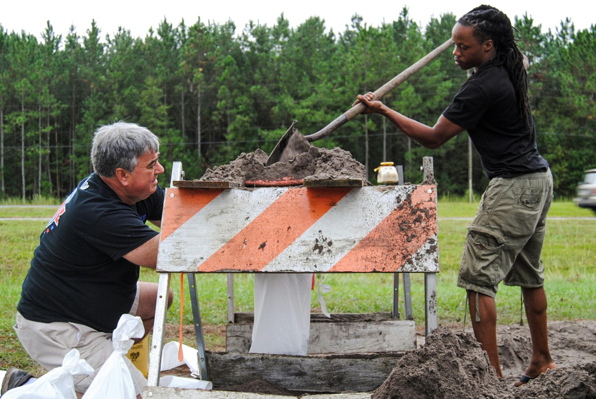 From left: Gainesville residents Erich Marzolf, 55, and Michael Haynes, 26, help each other make sandbags at the Alachua County Public Works Department's sandbag location, located at 11855 NW U.S. Highway 441, on Thursday morning. The men are strangers, but they are both working to prepare for possible Hurricane Matthew water buildup. “See if I can protect the front of my house," Marzolf said. "We don’t have gutters.”