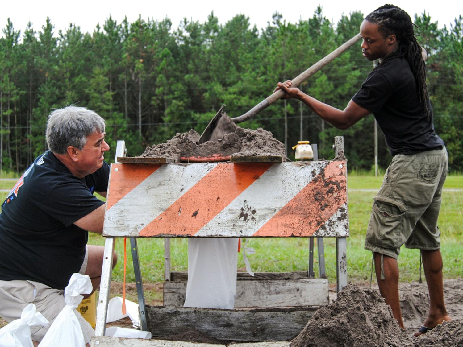 From left: Gainesville residents Erich Marzolf, 55, and Michael Haynes, 26, help each other make sandbags at the Alachua County Public Works Department's sandbag location, located at 11855 NW U.S. Highway 441, on Thursday morning. The men are strangers, but they are both working to prepare for possible Hurricane Matthew water buildup. “See if I can protect the front of my house," Marzolf said. "We don’t have gutters.”
