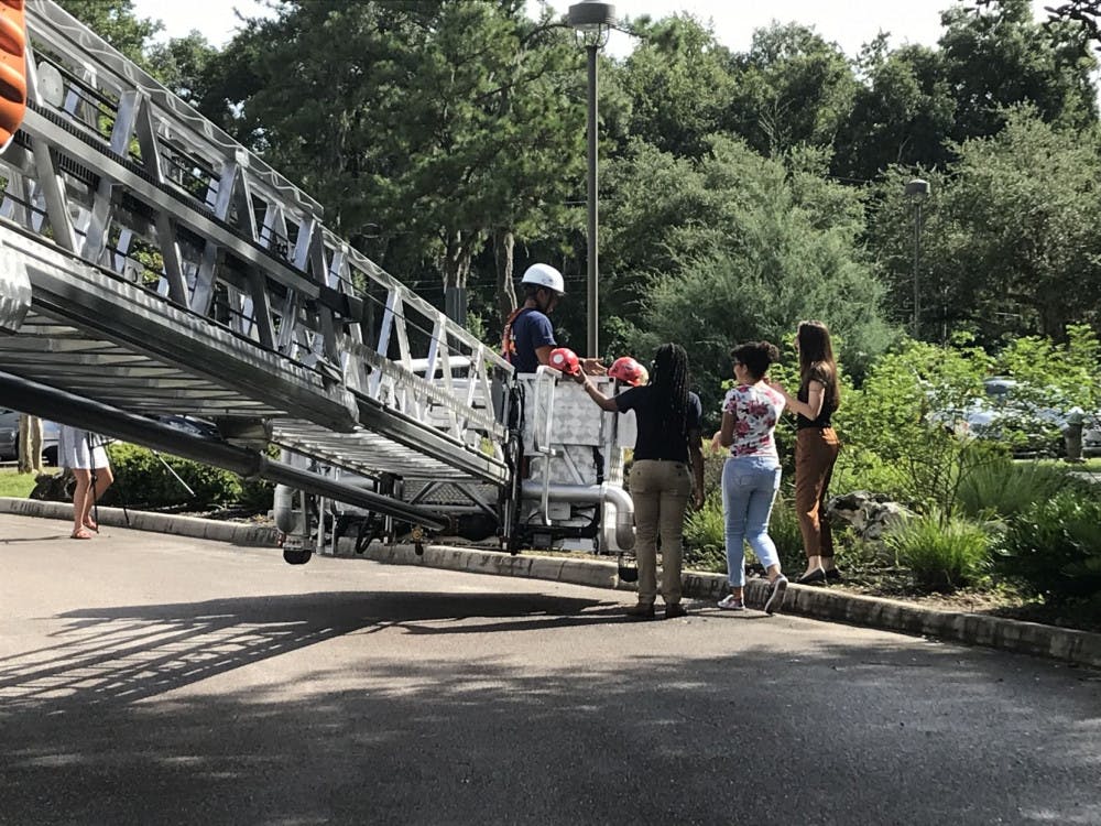 A Gainesville Fire Rescue firefighter, Jose Paredes, hands out helmets to attendees about to get into the aerial ladder’s basket.
&nbsp;