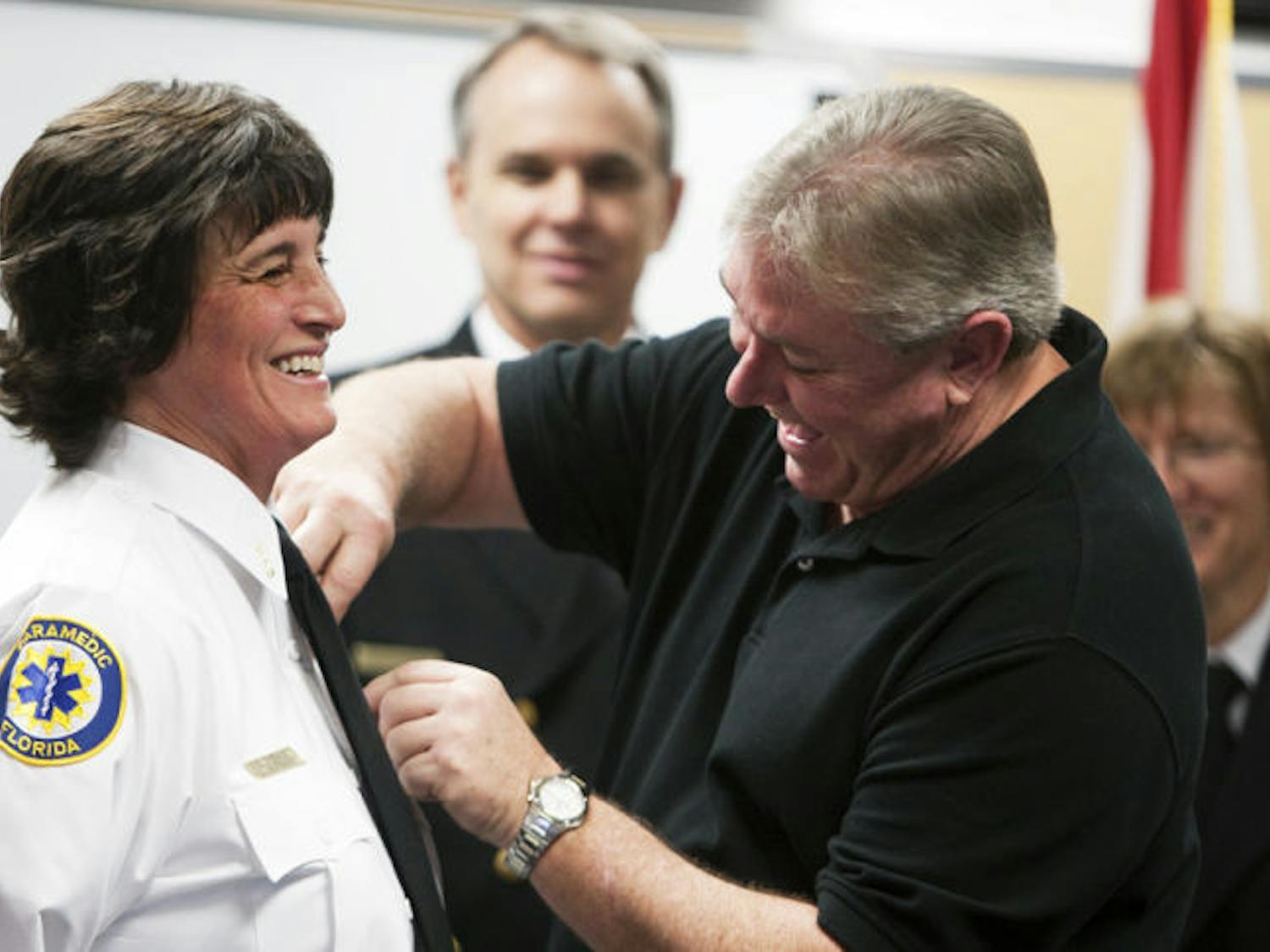 Elizabeth J. Braun receives a badge from her husband, George Braun, in honor of her promotion to lieutenant at a ceremony promoting Gainesville Fire Rescue members at about noon Thursday at the Support Services Bureau, 1026 NE 14 St.