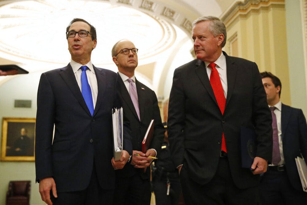 Treasury Secretary Steven Mnuchin, left, accompanied by White House Legislative Affairs Director Eric Ueland and acting White House chief of staff Mark Meadows, speaks with reporters as he walks to the offices of Senate Majority Leader Mitch McConnell of Ky. on Capitol Hill in Washington, Tuesday, March 24, 2020. (AP Photo/Patrick Semansky)