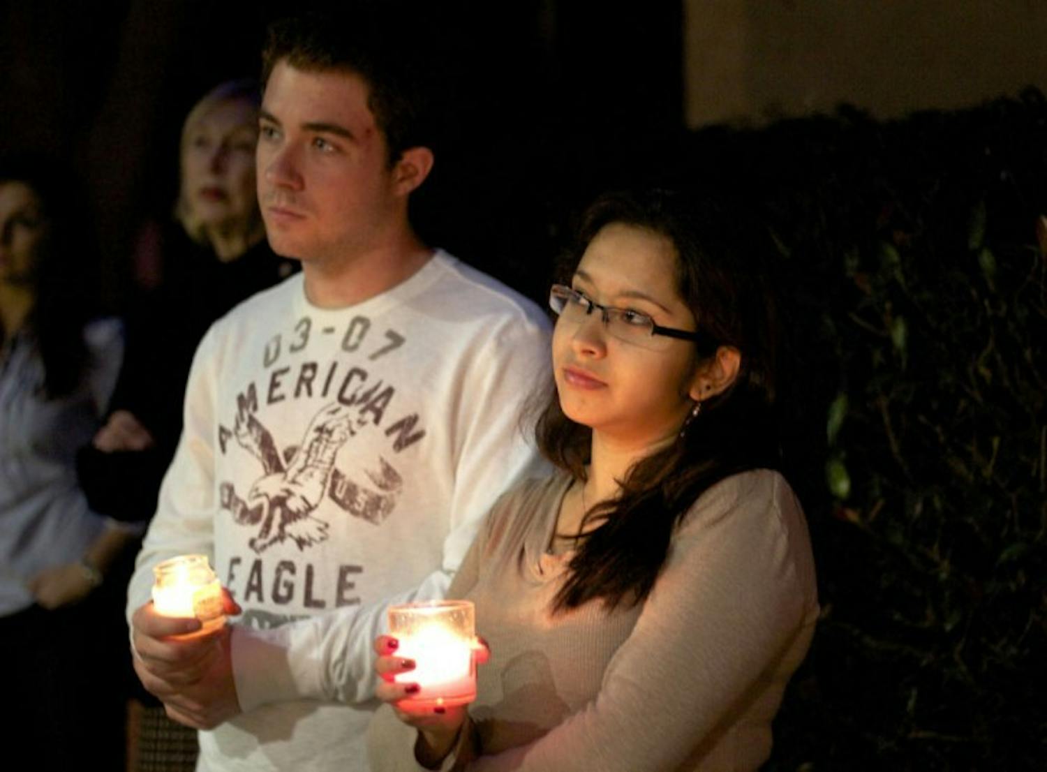 Linguistics junior David Sleeth, 20, and business senior Maria Novoa, 21, listen to Sen. Steve Oelrich comment about his rejection of a bill that would have granted U.S citizens of undocumented parents in-state tuition at a candlelight vigil on Friday.
