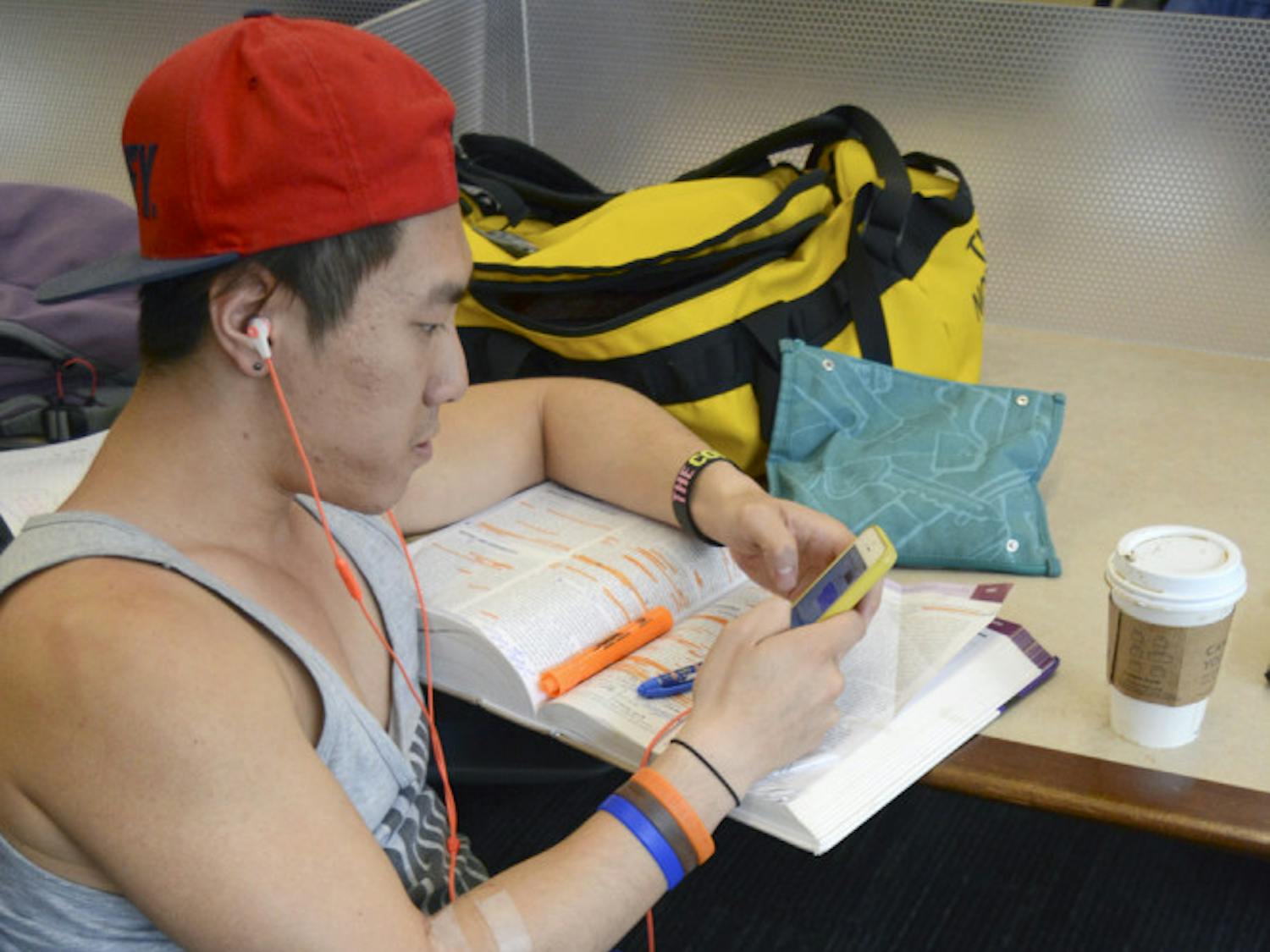 Thomas Sit, a 24-year-old UF public health graduate student, takes a break from his work to use his smartphone in Library West on Sunday. Sit said he probably accessed the internet more on his phone than his laptop, mainly because the phone was more convenient for him.