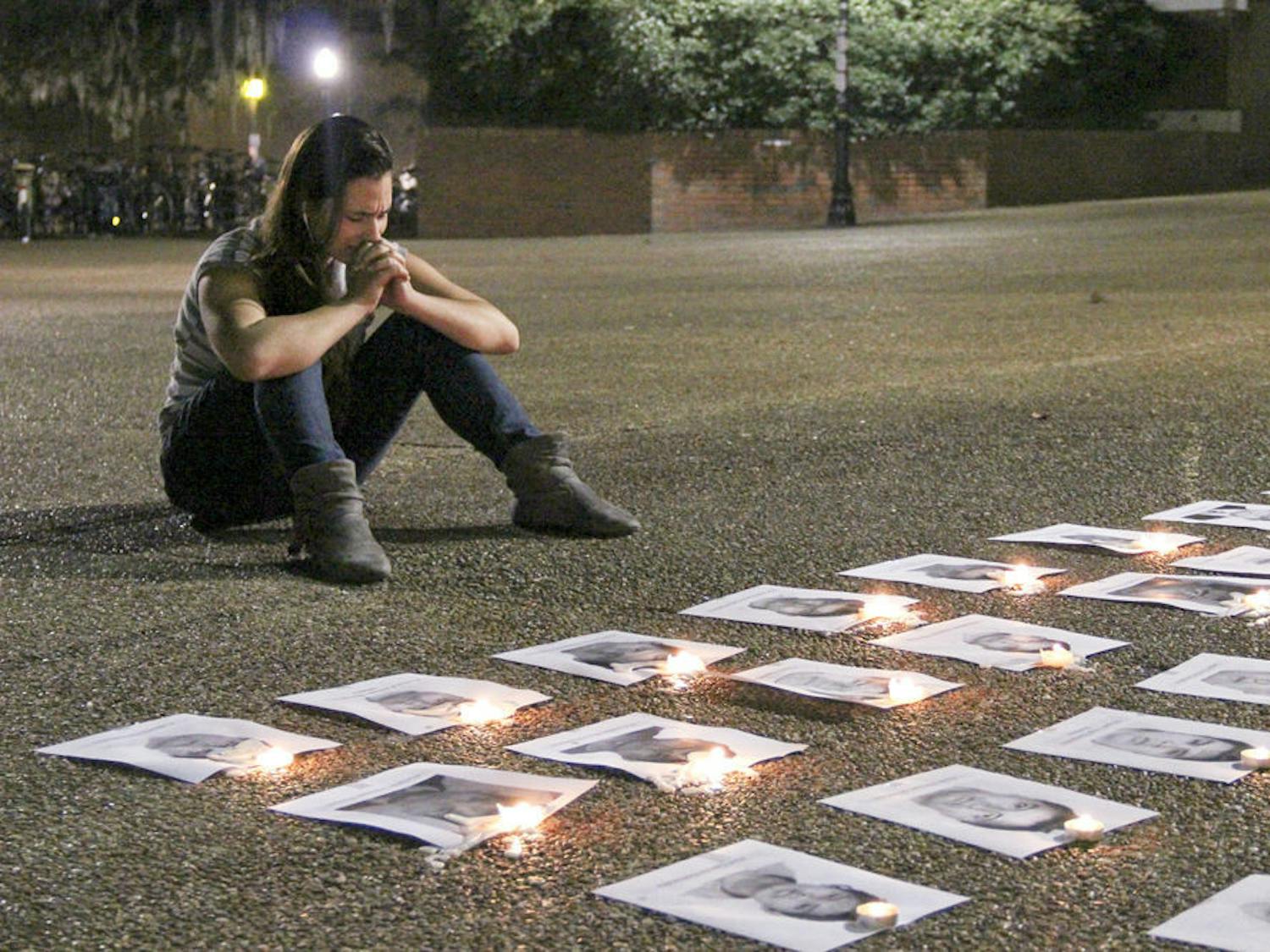 Michelle Zamperlini, an 18-year-old UF exploratory freshman, sits in front of the photos of the 43 protesters who went missing in Ayotzinapa, Mexico on Turlington Plaza Thursday evening. “One of them looks exactly like my cousin,” she says, as she clasps her hands in remembrance of the lives that were lost.