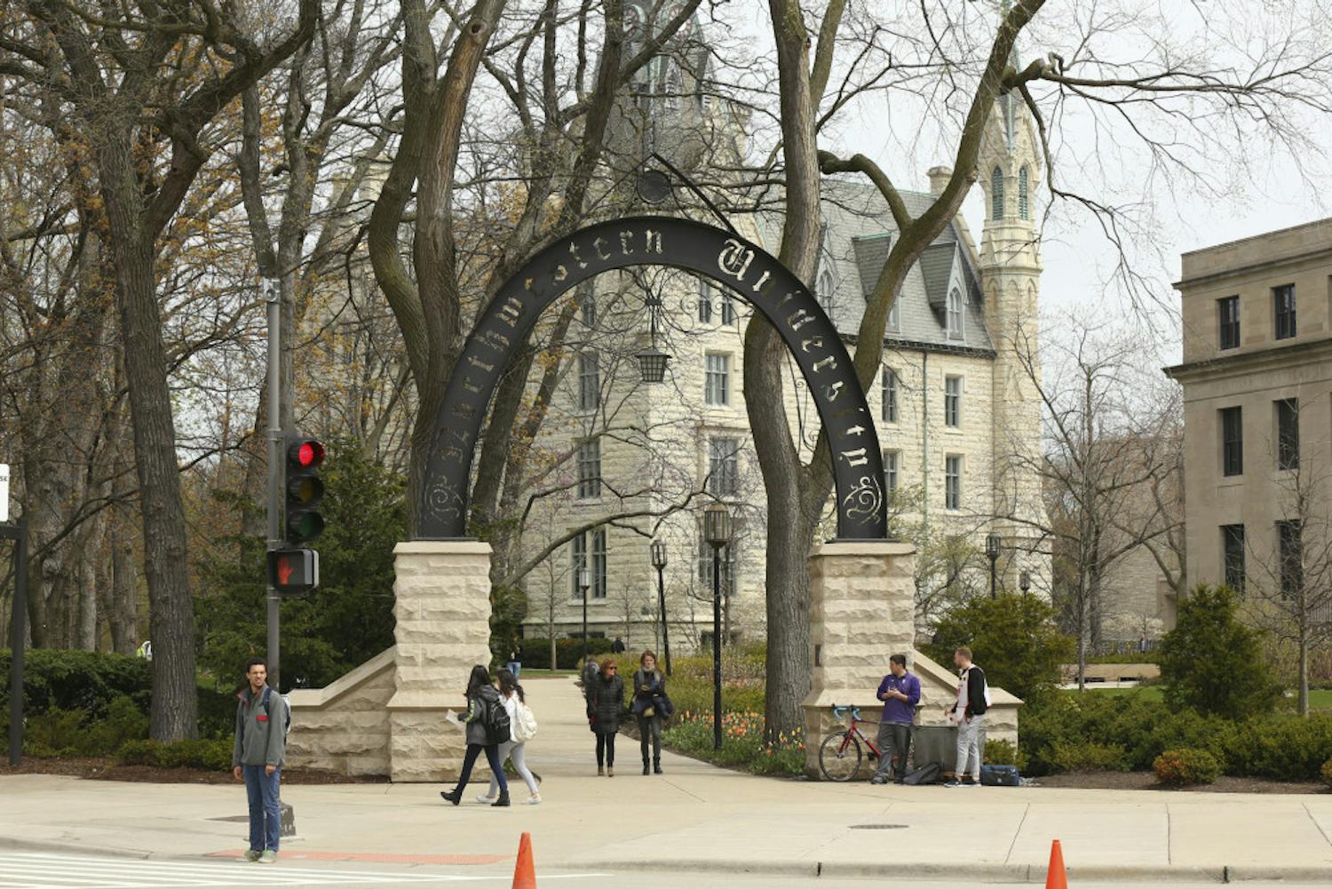 In this Friday, April 29, 2016, photo, people stand near the entrance gate to Northwestern University in Evanston, Ill. Northwestern University's student newspaper is under fire. Their first critics came from within the campus as student activists questioned journalists’ coverage of protests. Within days, editors decided to write a statement apologizing but their editorial prompted a second round of criticism from journalists around the country starting Monday, Nov. 11, 2019. (Chris Walker/Chicago Tribune via AP)