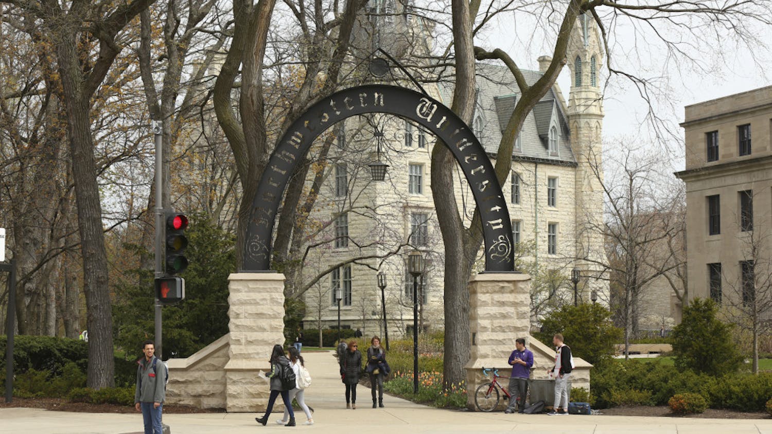 In this Friday, April 29, 2016, photo, people stand near the entrance gate to Northwestern University in Evanston, Ill. Northwestern University's student newspaper is under fire. Their first critics came from within the campus as student activists questioned journalists’ coverage of protests. Within days, editors decided to write a statement apologizing but their editorial prompted a second round of criticism from journalists around the country starting Monday, Nov. 11, 2019. (Chris Walker/Chicago Tribune via AP)