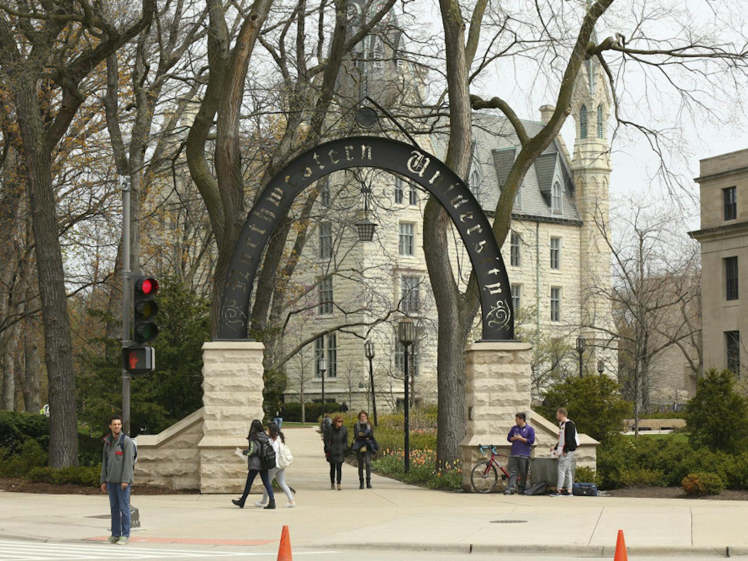 In this Friday, April 29, 2016, photo, people stand near the entrance gate to Northwestern University in Evanston, Ill. Northwestern University's student newspaper is under fire. Their first critics came from within the campus as student activists questioned journalists’ coverage of protests. Within days, editors decided to write a statement apologizing but their editorial prompted a second round of criticism from journalists around the country starting Monday, Nov. 11, 2019. (Chris Walker/Chicago Tribune via AP)