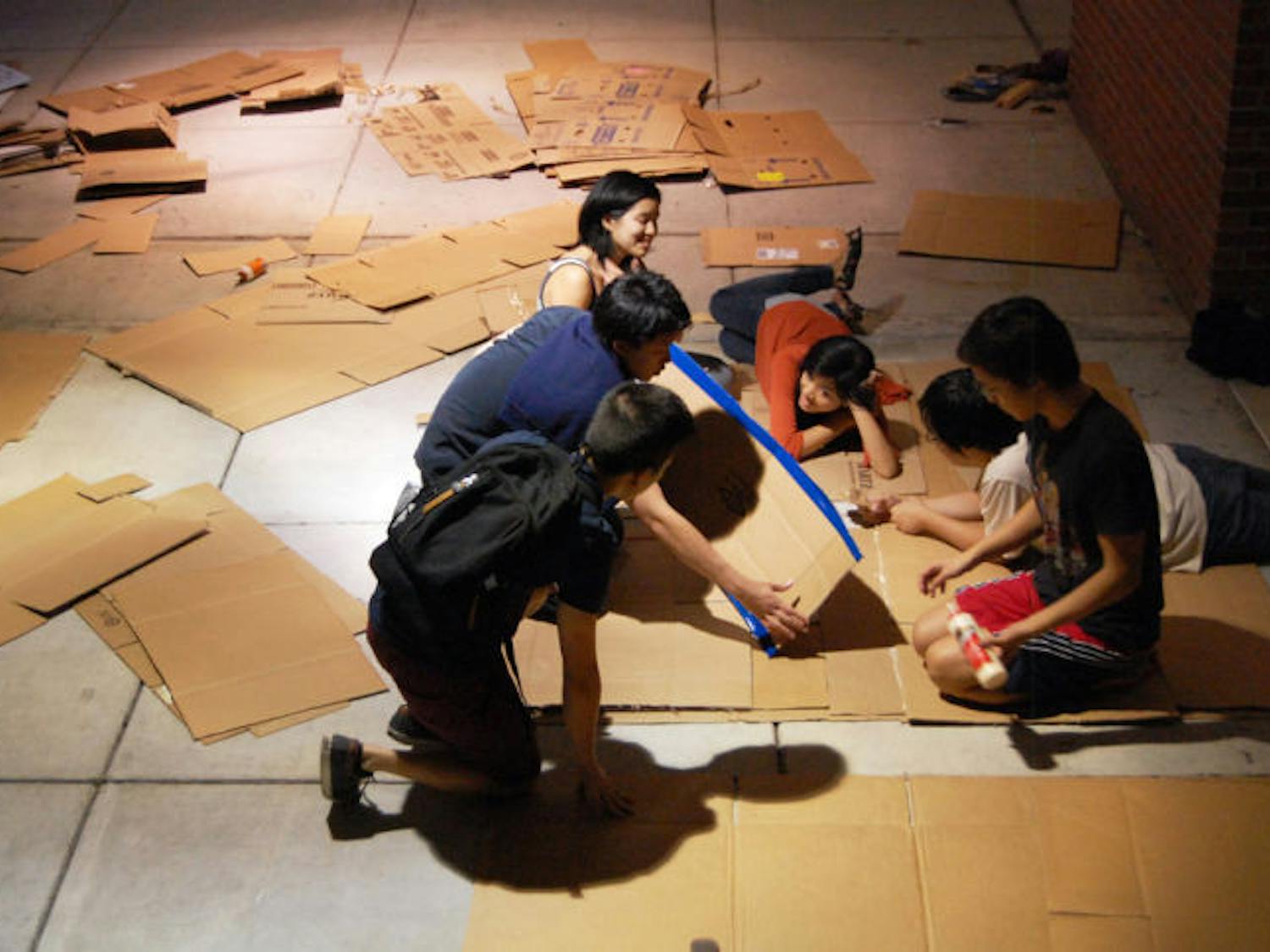 Members of UF’s Asian American Student Union prepare cardboard mats in the Reitz Union breezeway Wednesday evening for the Cardboard Ox activity, which was held during the AASU Field Day on Monday.