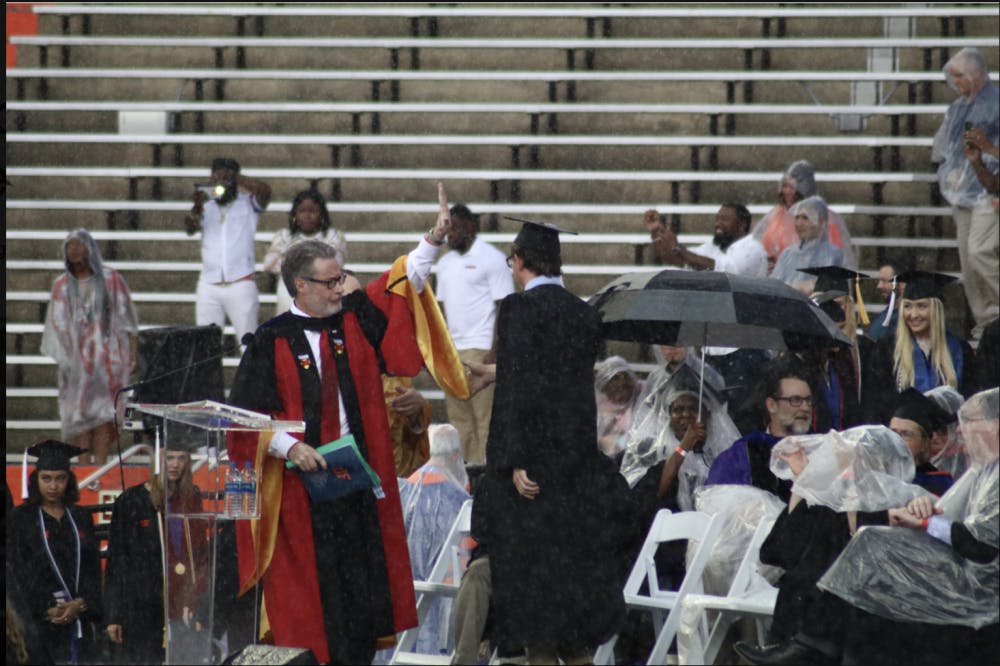 College of Liberal Arts and Sciences Dean, David Richardson, gestures to pause the commencement ceremony. Richardson announced the ceremony would be delayed by 30 minutes, but the ceremony was later moved to an insidehallway of the stadium.