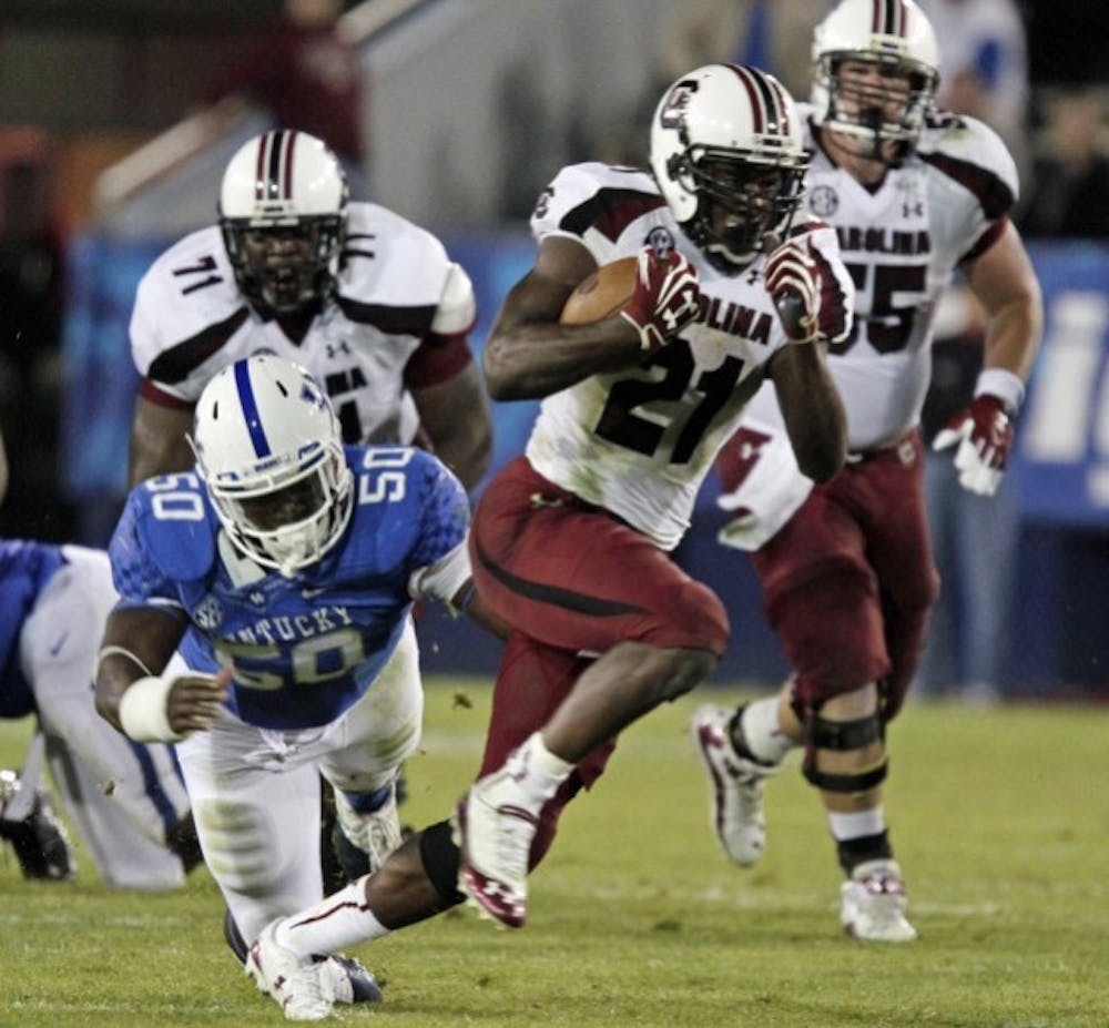<p>South Carolina tailback Marcus Lattimore (21) runs away from Kentucky's Mike Douglas (50) during the second half of an NCAA college football game in Lexington, Ky., on Sept. 29. Then No. 6 South Carolina came from behind to beat Kentucky 38-17.</p>