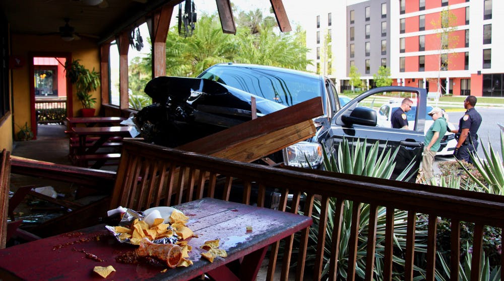 Police question Brian Wilson Samuel, 59, next to his pickup truck. His truck crashed through the railing and damaged two benches and windows at La Tienda Latina restaurant, located at 2204 SW 13th St.