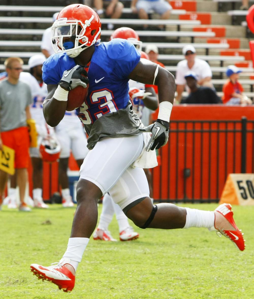 <p>Mack Brown (33) runs a drill during open practice at Ben Hill Griffin Stadium.</p>