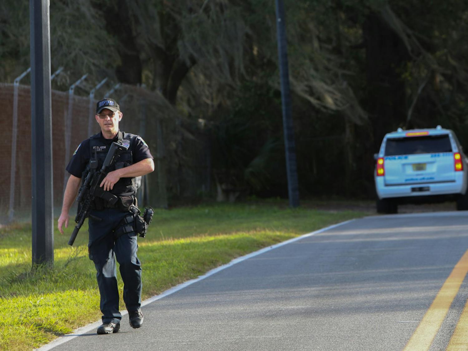 A University of Florida Police Department officer walks towards his vehicle Friday after searching a wooded area near the UF College of Veterinary Medicine for a suspect reportedly firing a gun at targets.