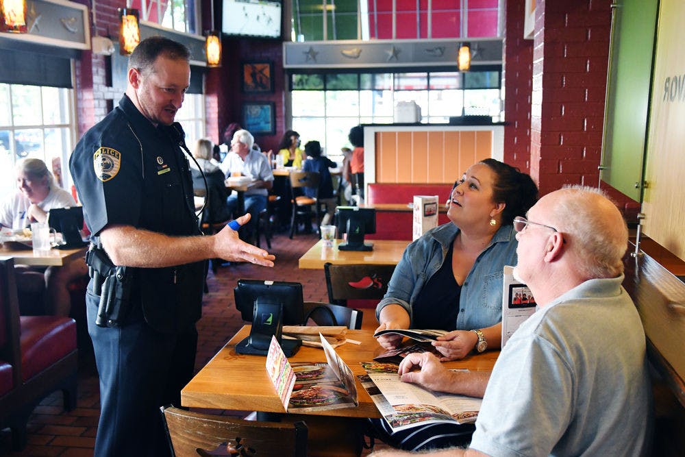 Gainesville Police Officer Travis Stephens discusses the St. Jude Children’s Hospital fundraiser with Christina and David Lampp. GPD officers waited tables on the last day of Chili’s fundraising event, which was a “donate profits” day.