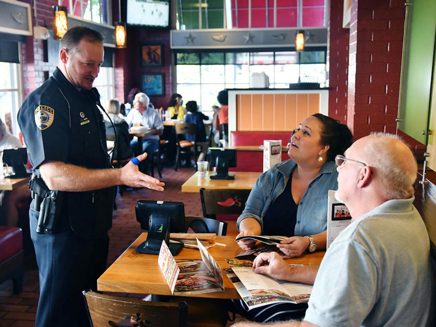 Gainesville Police Officer Travis Stephens discusses the St. Jude Children’s Hospital fundraiser with Christina and David Lampp. GPD officers waited tables on the last day of Chili’s fundraising event, which was a “donate profits” day.