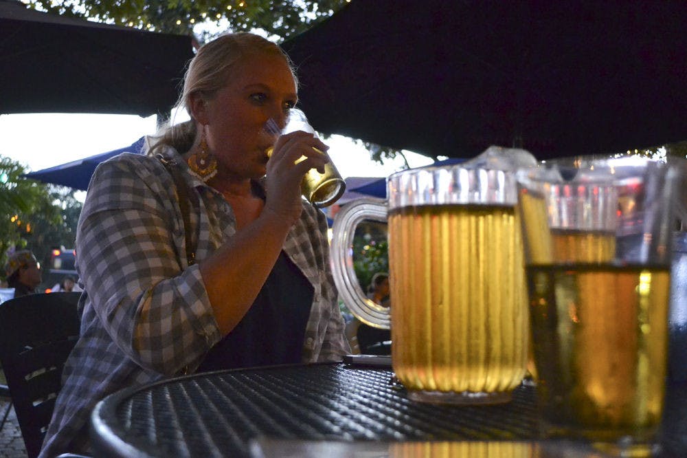 <p>Mary Myers, a 22-year-old UF family, youth and community sciences senior, sips from her beer at The Swamp Restaurant on Oct. 13, 2015. Myers said when game day rolls around she comes to the restaurant with her friends because it has a fun outside atmosphere.</p>