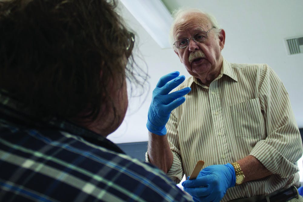 <p dir="ltr">Dr. Fred West examines a patient, who complains of pain in the mouth after having his teeth removed, at an open wound clinic in Grace Marketplace on March 27.</p>