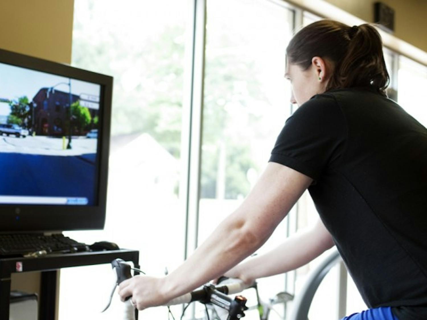 Amie Buehler, a 23-year-old applied physiology and kinesiology senior and intern at Shands Fitness and Wellness Center, demonstrates how the Virtual Tour de Shands operates Wednesday afternoon.