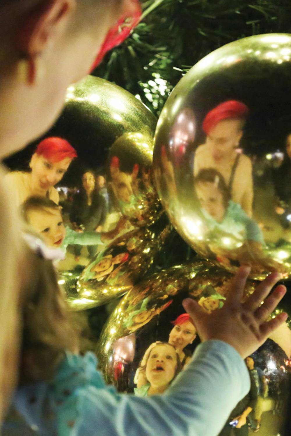<p>Kelly Anderson, a 30-year-old clinical lab scientist, and Olivia Hamner, 14 months old, look at their reflections on Christmas decorations after the tree lighting ceremony on Nov. 29, 2015.</p>