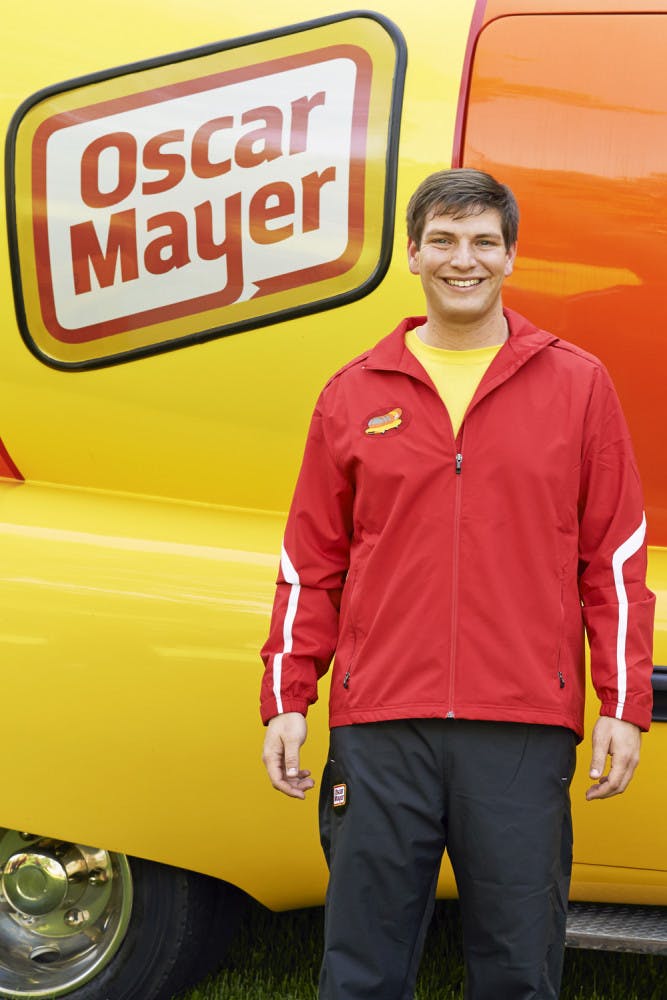 Spencer Smud, the 24-year-old “Hotdogger” who drives one of the Wienermobiles, poses for a photo in front of the hot dog-shaped vehicle.