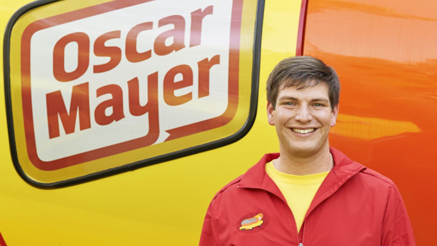 Spencer Smud, the 24-year-old “Hotdogger” who drives one of the Wienermobiles, poses for a photo in front of the hot dog-shaped vehicle.