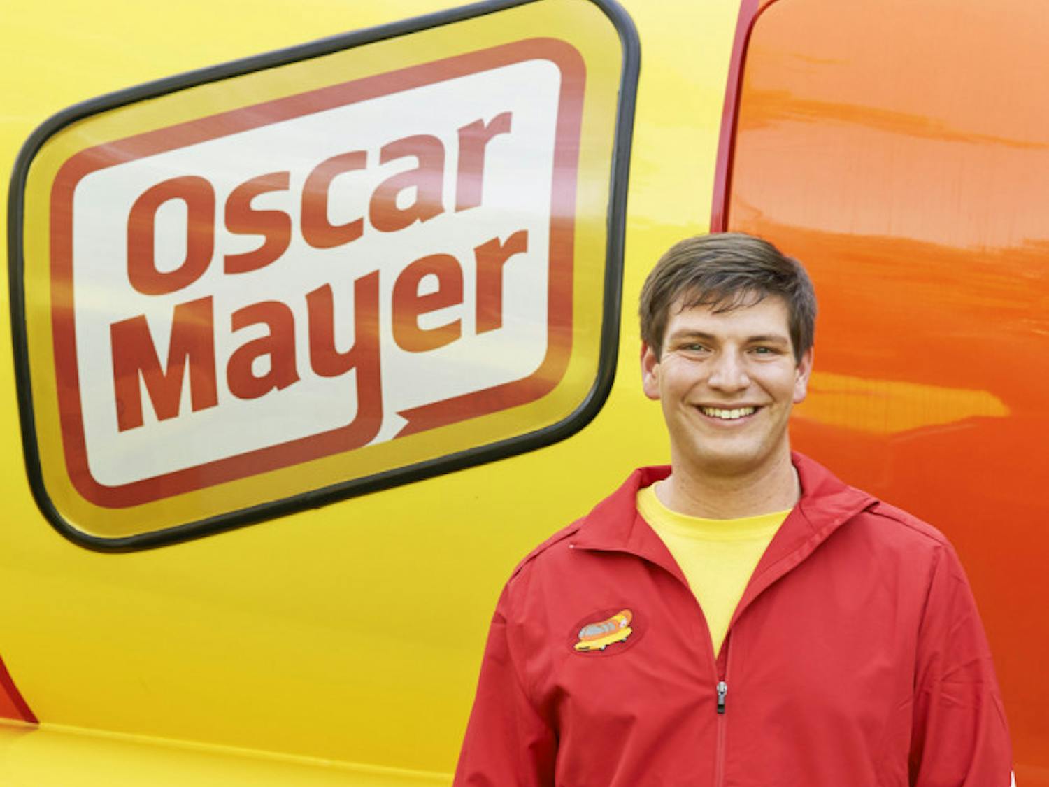 Spencer Smud, the 24-year-old “Hotdogger” who drives one of the Wienermobiles, poses for a photo in front of the hot dog-shaped vehicle.