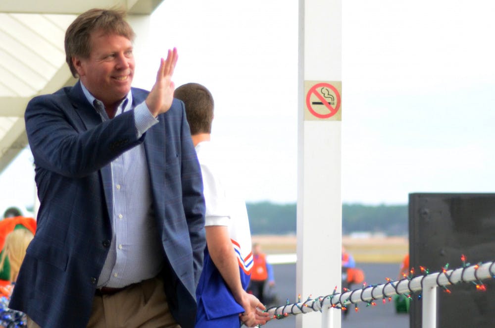 Jim McElwain waves as he walks off the plane after arriving in Gainesville on Dec. 5, 2014.