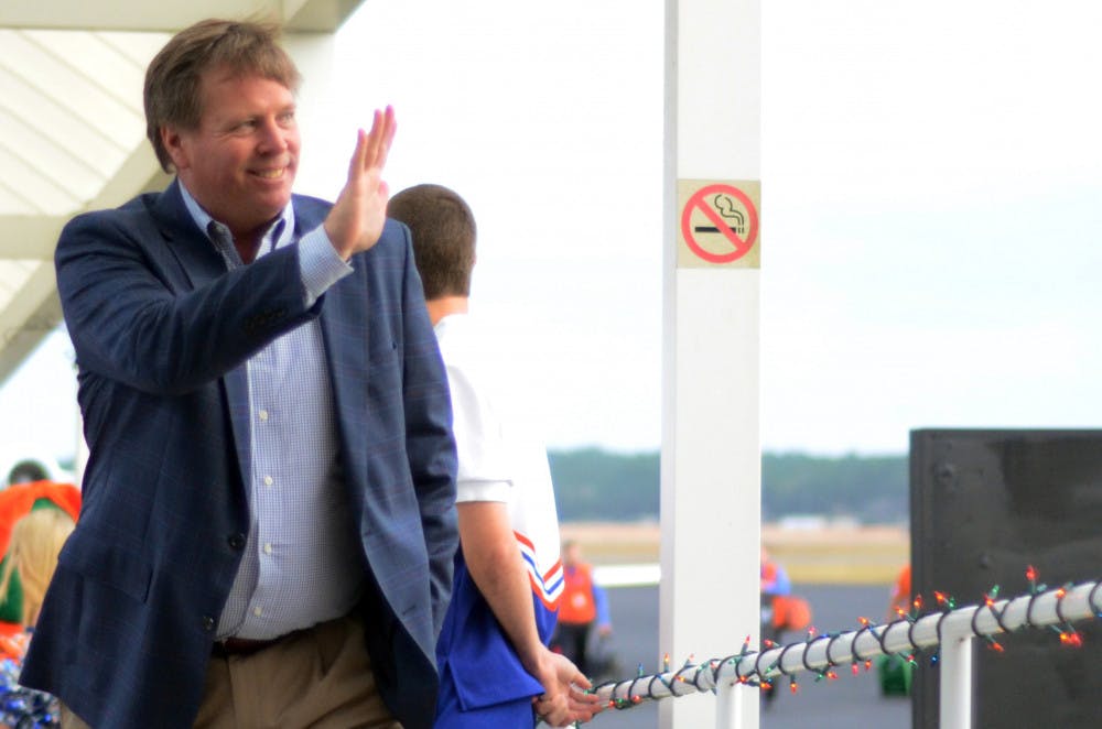 <p>Jim McElwain waves as he walks off the plane after arriving in Gainesville on Dec. 5, 2014.</p>